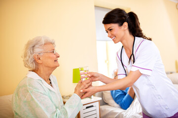 Obraz premium Caring young female doctor bringing glass of water to her patient