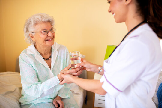 Brunette lady doctor and her nursing home elder woman patient having polite conversation
