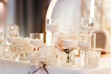 Candles in the glass candlesticks and flowers as a background. Blurred flowers background. Place for your text