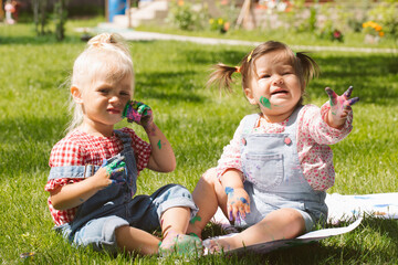 Two little girls sisters paint with finger paints