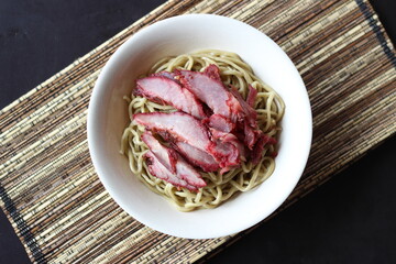 a bowl of noodle with red pork meat slices