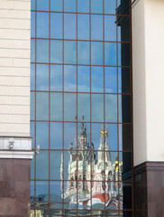       Reflection of the Orthodox Church in the mirrored facade of the administrative building.   