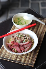 A bowl of noodle with pork and chicken meat and clear healthy soup