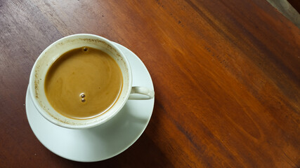 Milk coffee in a white cup against a wooden table background