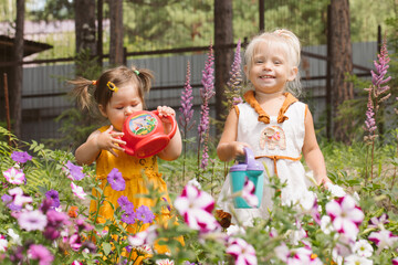Two little girls sisters watering flowers