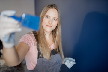 Happy painter worker woman using blue paint brush working in new house