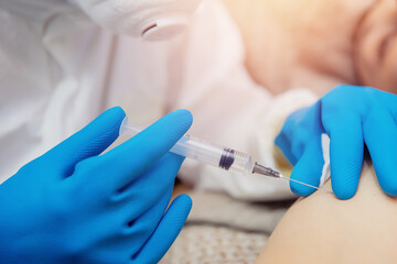 Close-up vaccination inoculation of patient in shoulder, syringe with covid vaccine flu is injected into sick man