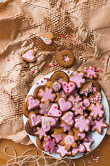 Ginger cookies with pink sugar glaze, rainbow sprinkles and red sugar hearts on kraft paper