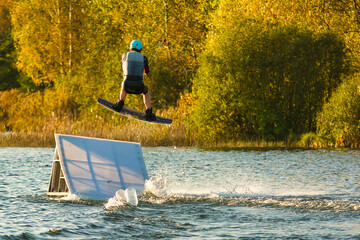 Wakeboarder making tricks. Low angle shot of man wakeboarding on a lake. Man water skiing at sunset.