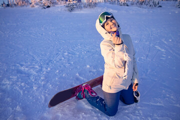 Happy young woman snowboarder smiling after going downhill on snowboard