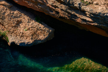 Clear and transparent river water and some big rocks illuminated by the sun