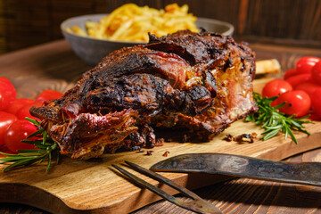 Baked lamb leg on wooden cutting board with garnish