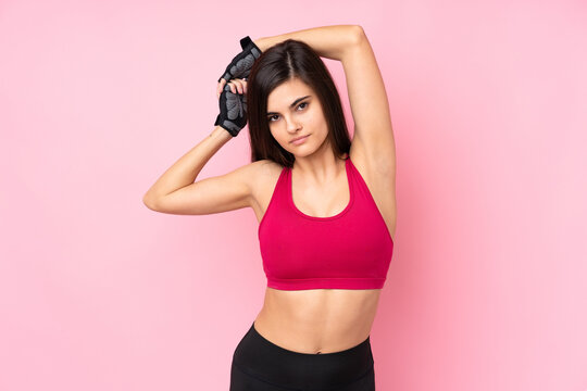 Young sport woman over isolated pink background stretching © luismolinero
