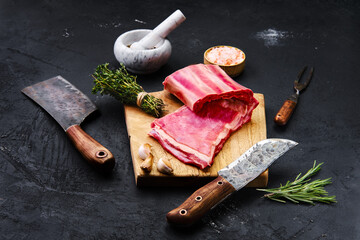 Raw lamb breast ribs on wooden cutting board with herbs and seasoning