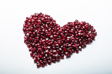 Heart shape pomegranate seeds on white background.  Valentines helthy love concept.