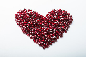 Obraz na płótnie Canvas Heart shape pomegranate seeds on white background. Valentines helthy love concept.