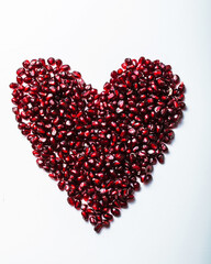 Fototapeta na wymiar Heart shape pomegranate seeds on white background. Valentines helthy love concept.