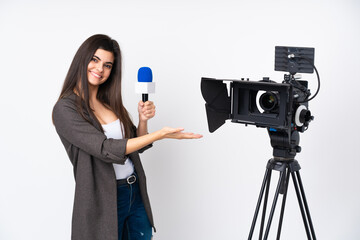 Reporter woman holding a microphone and reporting news over isolated white background extending hands to the side for inviting to come