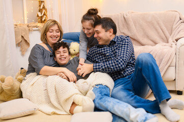 portrait of a family sitting on a sofa at home, four people having fun together