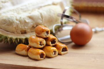 shiny looking cookies with durian, egg, and mixer on a wooden board