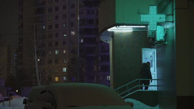Snowfall, a girl goes to a pharmacy for medicines, a night city, a green cross.