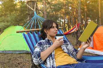 Woman with book resting in comfortable hammock outdoors