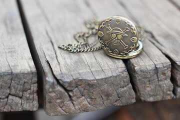 one piece vintage pocket watch with skull engraving on a wooden table
