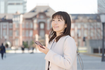 東京駅でスマートフォンで通話する女性