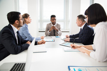 Group of business people sitting around the office desk and discussing the project