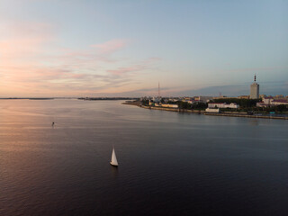 September, 2020 - Arkhangelsk. White yacht with a white sail on the background of the city of Arkhangelsk. Northern Dvina River. Arkhangelsk port. Russia, Arkhangelsk region