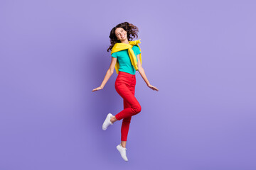 Full length photo of funny charming curly young lady wear sweater shoulders jumping high isolated...