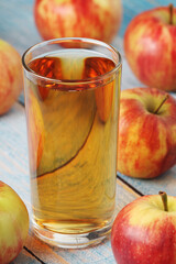 A glass with apple juice and ripe apples