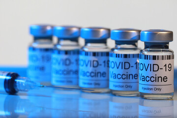 Blue filter light effect of Covid-19 vaccine injection vials medicine drug bottles and syringe. Covid-19 vaccination, immunization, treatment to cure Corona Virus infection. Soft focus image.