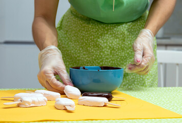 The process of glazing chocolate marshmallows on a stick. Selective focus.