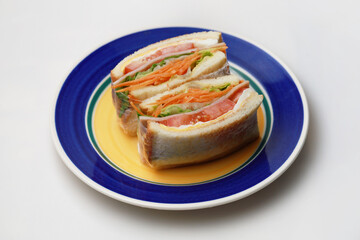 Sandwich with ham, egg, tomatoes, lettuce and toasted bread on a plate. High angle view isolated on white background.