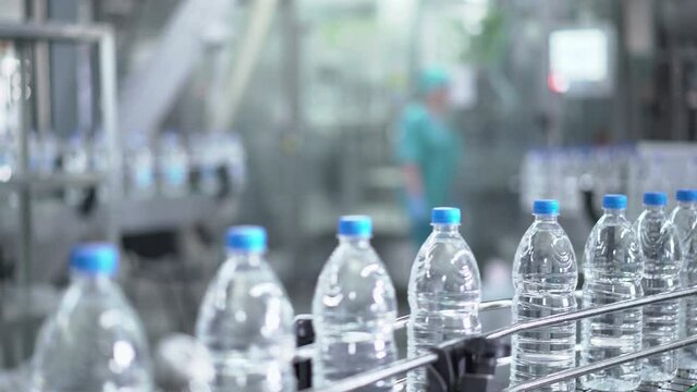 Plastic water bottles on conveyor and water bottling machine industry.