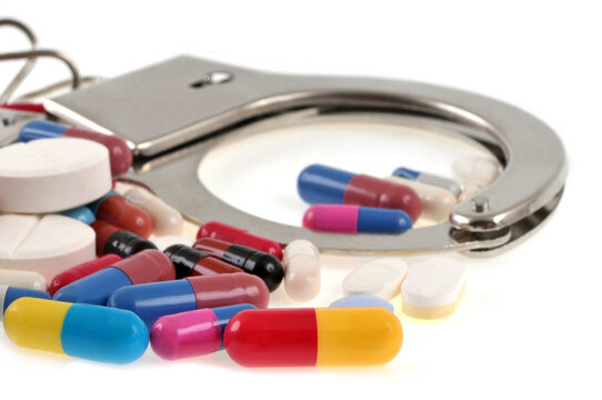 Concept de trafic de drogue avec des menottes et des stup&eacute;fiants en gros plan sur fond blanc