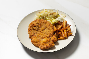Breaded beef cutlets served with french fries and salad