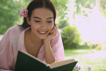 Fototapeta premium Beautiful young woman reading book in park on sunny day