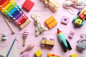 Different toys on pink wooden background, flat lay