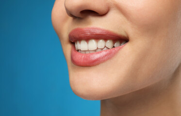 Obraz premium Woman with healthy teeth and beautiful smile on blue background, closeup. Cosmetic dentistry