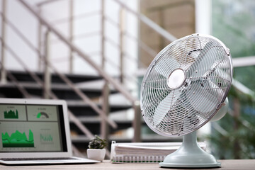 Modern electric fan on table in office. Space for text