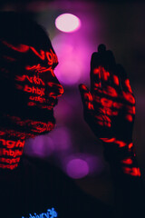 Young man with red letters on his face in the dark.