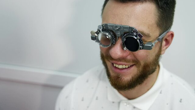 Smiling happy male patient in corrective testing glasses. Checking up eyesight in clinic. Handsome patient in ophthalmology.