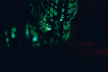 Young man with geen letters on his head in the dark.