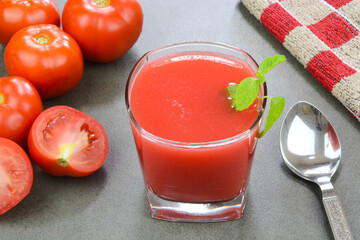 Freshly prepared tomato juice with red tomatoes in the background