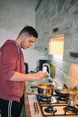 Man cooking pasta spaghetti at home in the kitchen. Guy cooking a tasty meal.