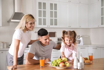 Happy family having breakfast together at table in modern kitchen