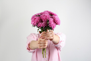 Woman with bouquet of beautiful asters on light background, closeup. Autumn flowers