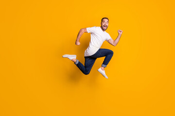 Fototapeta na wymiar Full length body size side profile photo of jumping man running fast isolated vibrant yellow color background